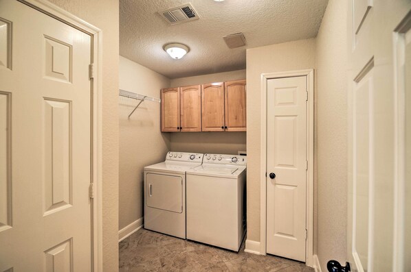 A laundry room with a washer and dryer, wooden cabinets, and a door. - Apt w/ Balconies - Steps to Kemah Boardwalk! (Kemah)