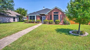 A two-story brick house with a front yard, a pathway leading to the front door, and a small tree in the front yard. - Family-friendly Rowlett Home ~ 23 Mi to Dallas (Rowlett)