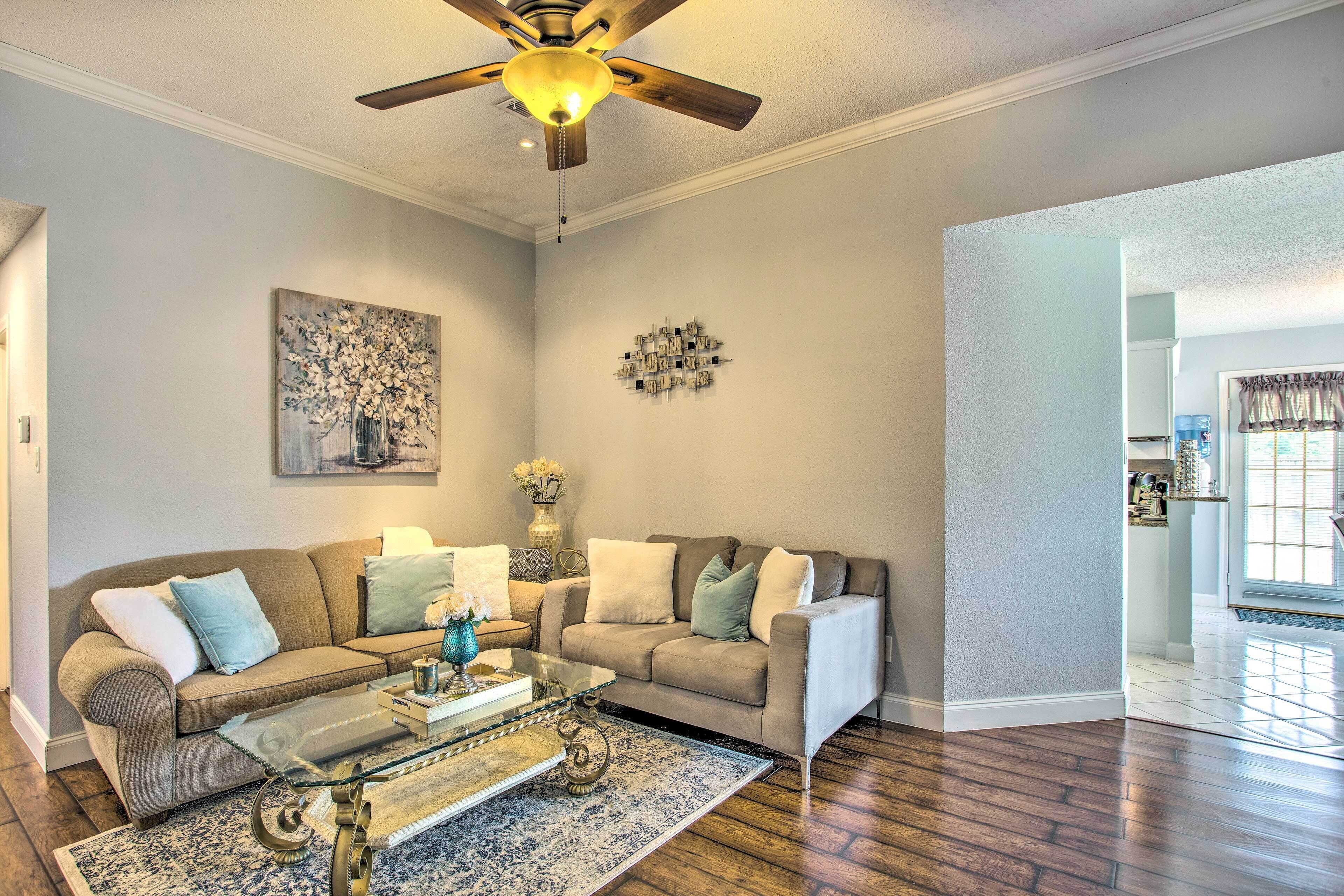 A living room with a beige sofa, a glass coffee table, and a patterned rug.