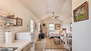 A compact kitchen with a sink, stove, and shelves; a bedroom with a bed and a dresser; and a dining area with a table and chairs. - On-site Pond & Fire Pit: Montague Retreat! (Montague)