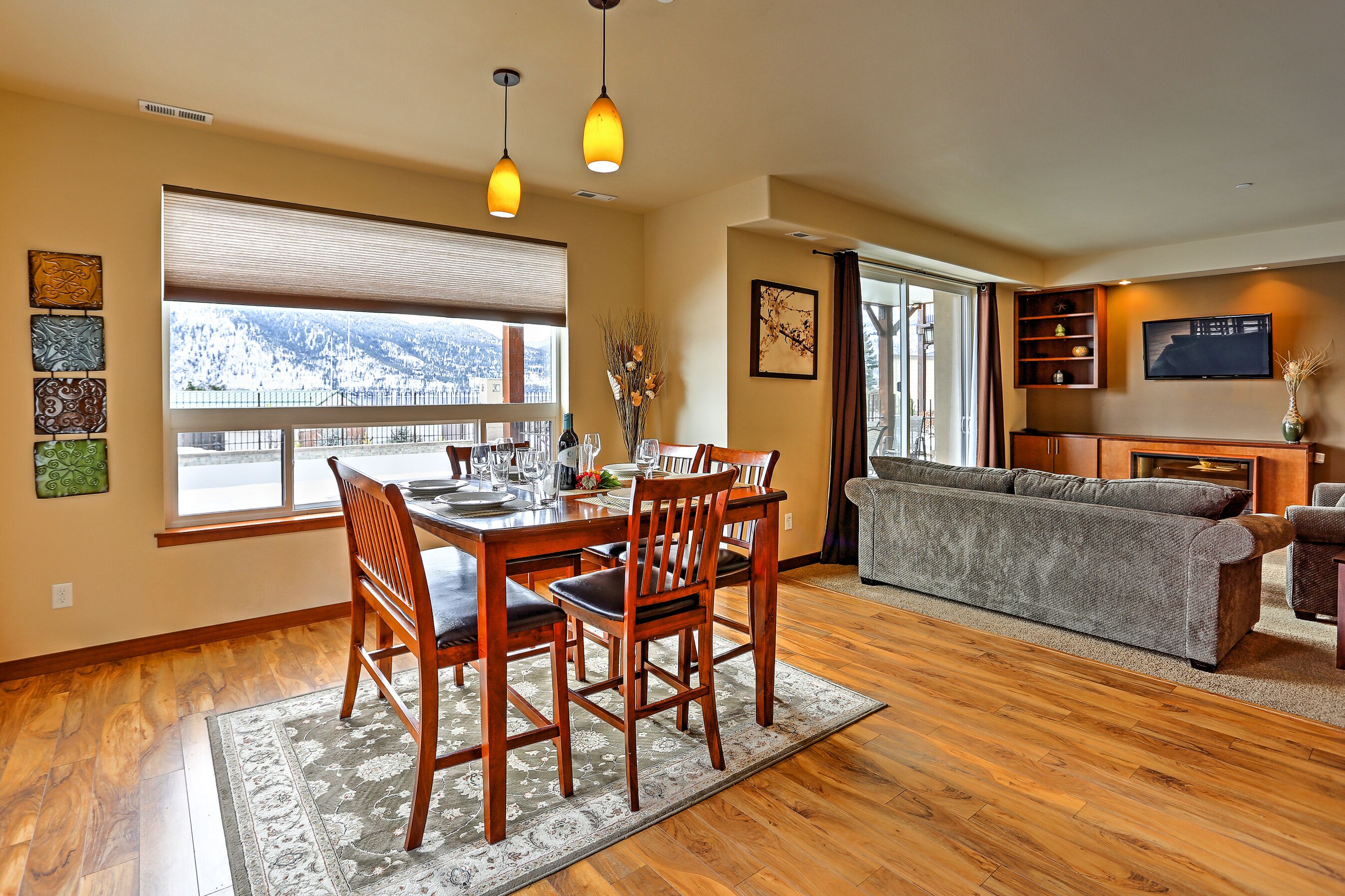 A dining area with a wooden table and chairs, a sofa, and a TV in the living room.