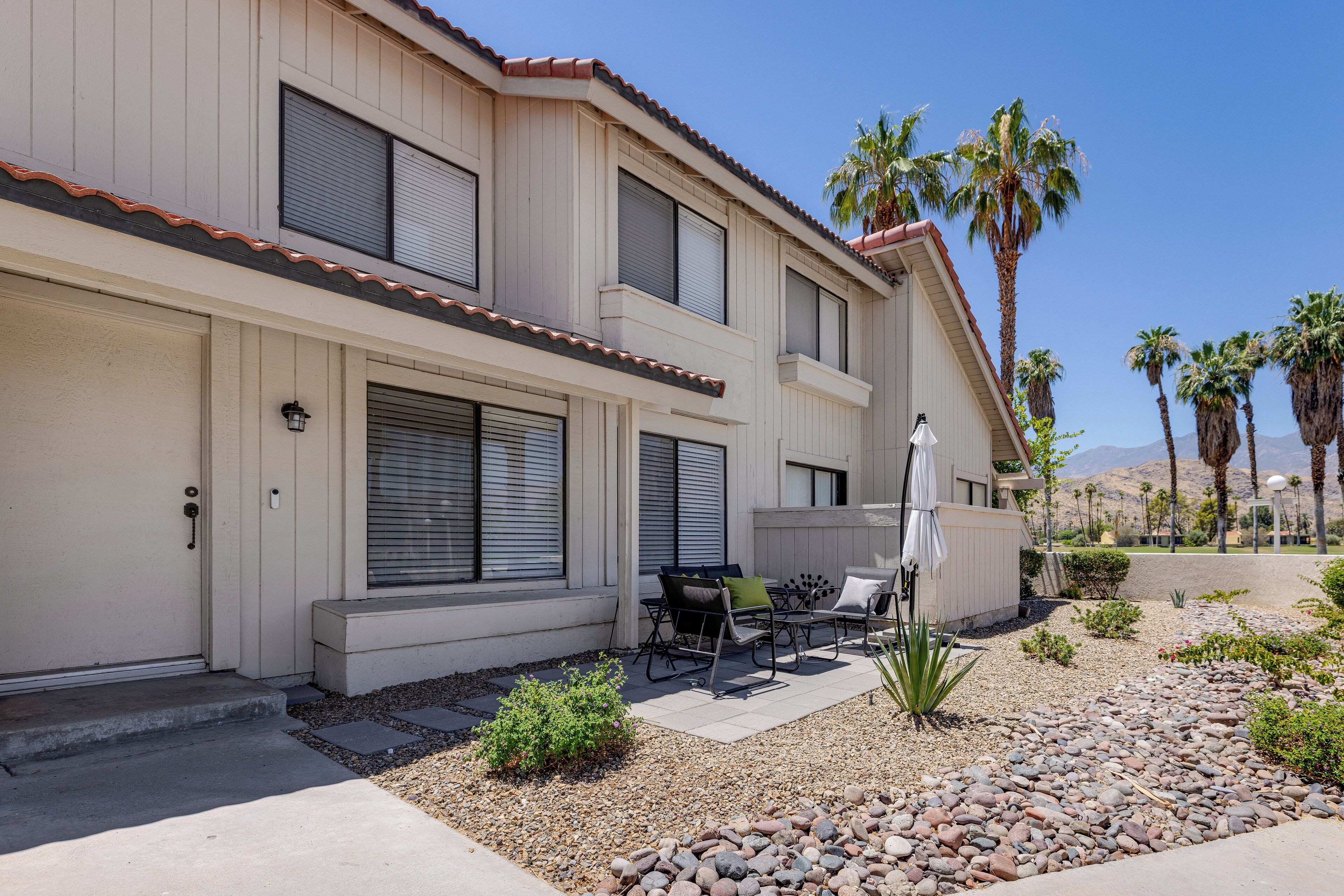A two-story building with a patio area featuring outdoor furniture and a small garden.