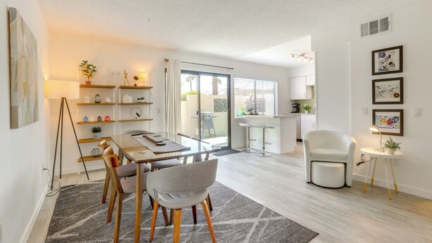 Un salón moderno con comedor, un sillón blanco y una mesita auxiliar con una planta.