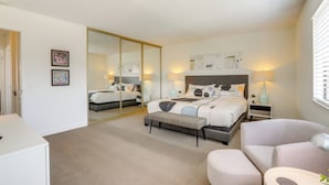 Un dormitorio moderno con una cama grande, un banco, un escritorio y un armario.