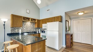 A kitchen with wooden cabinets, a black countertop, a white refrigerator, and a bar stool. - 4 Mi to Cherry Grove Beach: Studio w/ Pool Access (Little River)