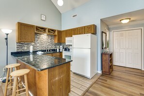 A kitchen with wooden cabinets, a black countertop, a white refrigerator, and a bar stool. - 4 Mi to Cherry Grove Beach: Studio w/ Pool Access (Little River)