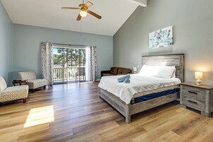 A bedroom with a bed, a nightstand, a chair, a ceiling fan, and a window with curtains.