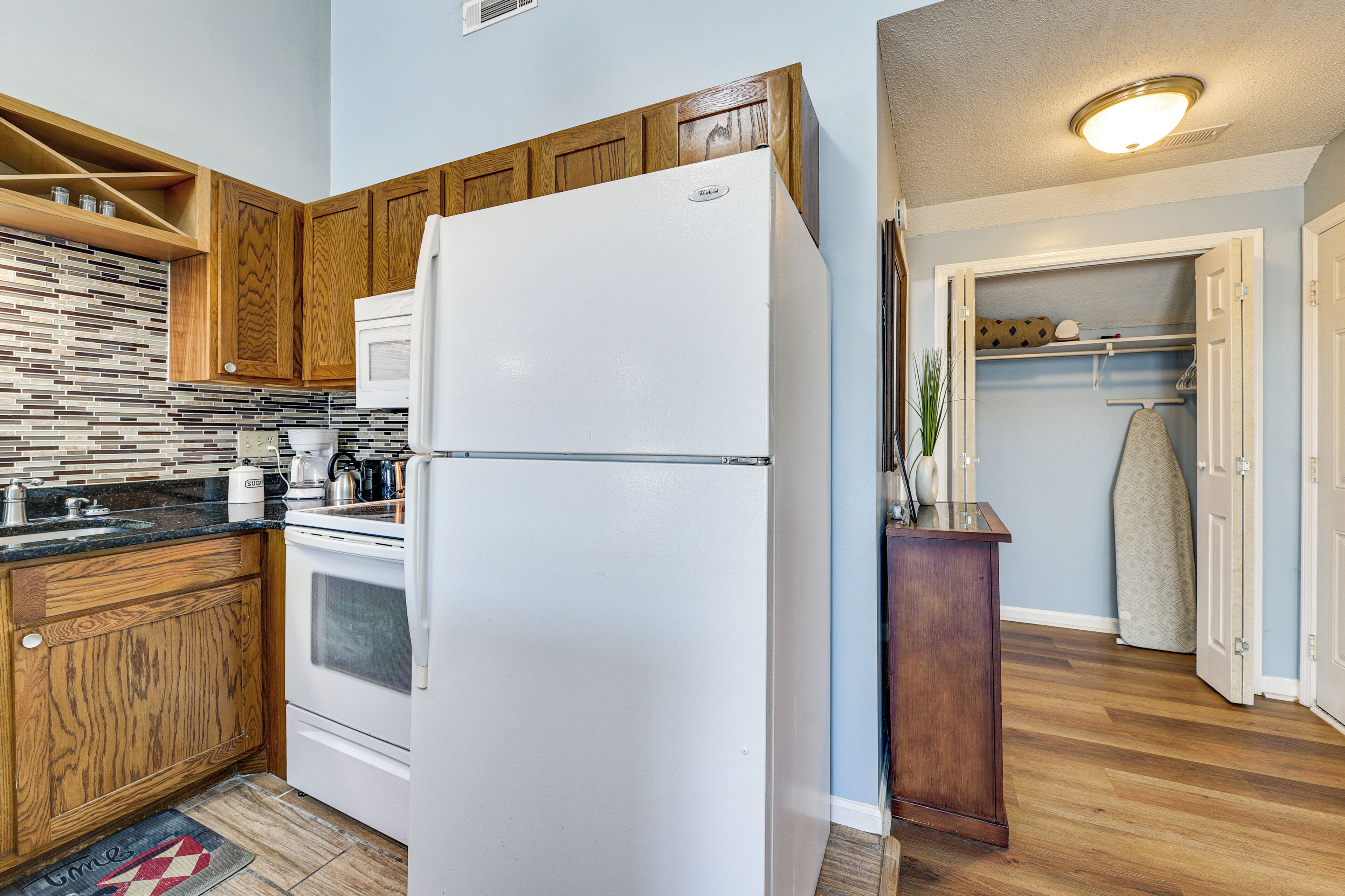 A kitchen with wooden cabinets, a white refrigerator, and a tiled backsplash.