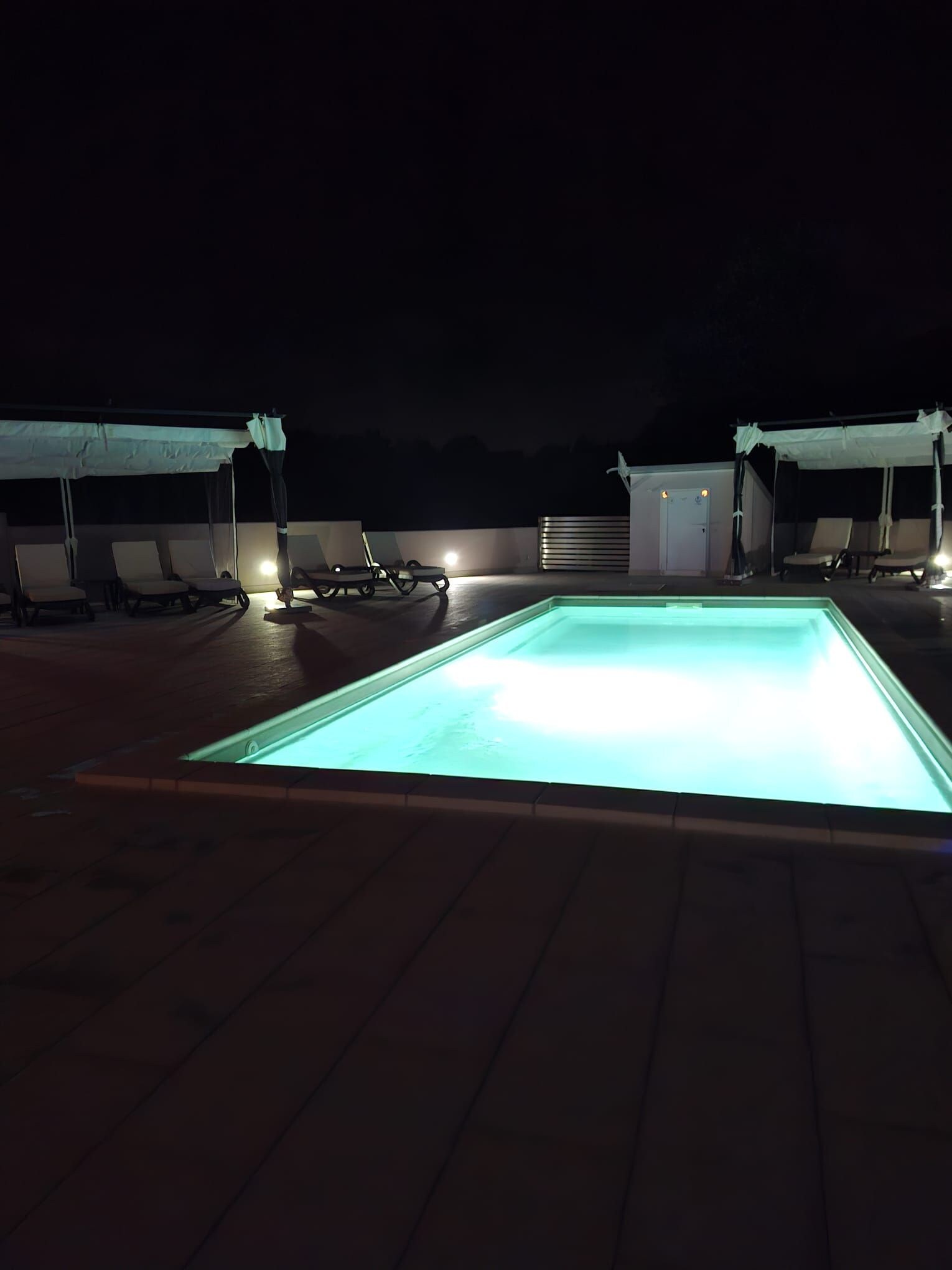 Piscina no terraço com espreguiçadeiras e área coberta.
