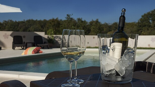 A poolside setting with a glass of white wine and a bottle of wine in an ice bucket. - APP1 Romantic villa with pool - 5 min from the beach! (Novigrad)
