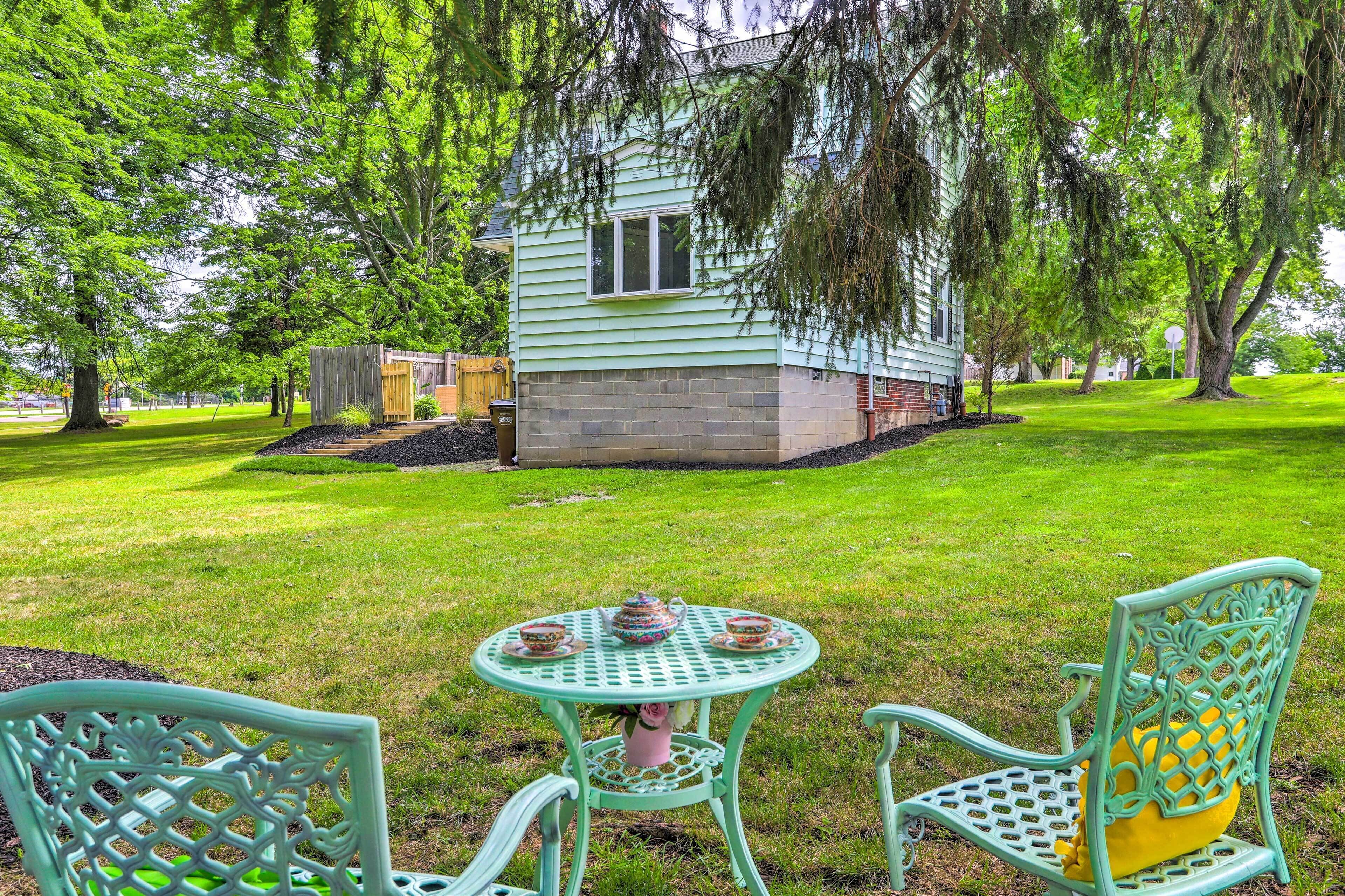 A green house with a small porch, surrounded by a well-maintained lawn and trees.