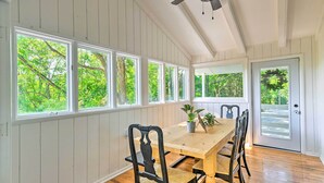 A dining area with a wooden table and chairs, large windows with a view of trees, and a door with a wreath. - Stylish Franklin Cabin on 6 Private Acres! (Franklin)