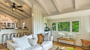 A spacious living area with a white sofa, a wooden coffee table, and a view of the outdoors through large windows. - Stylish Franklin Cabin on 6 Private Acres! (Franklin)