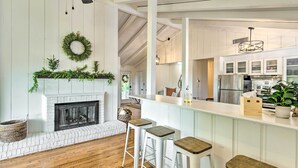 A modern kitchen with white cabinetry, a wooden ceiling, and a fireplace with greenery. - Stylish Franklin Cabin on 6 Private Acres! (Franklin)