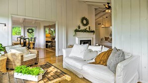 A spacious living room with a white sofa, wicker chairs, a wooden coffee table, and a fireplace. - Stylish Franklin Cabin on 6 Private Acres! (Franklin)
