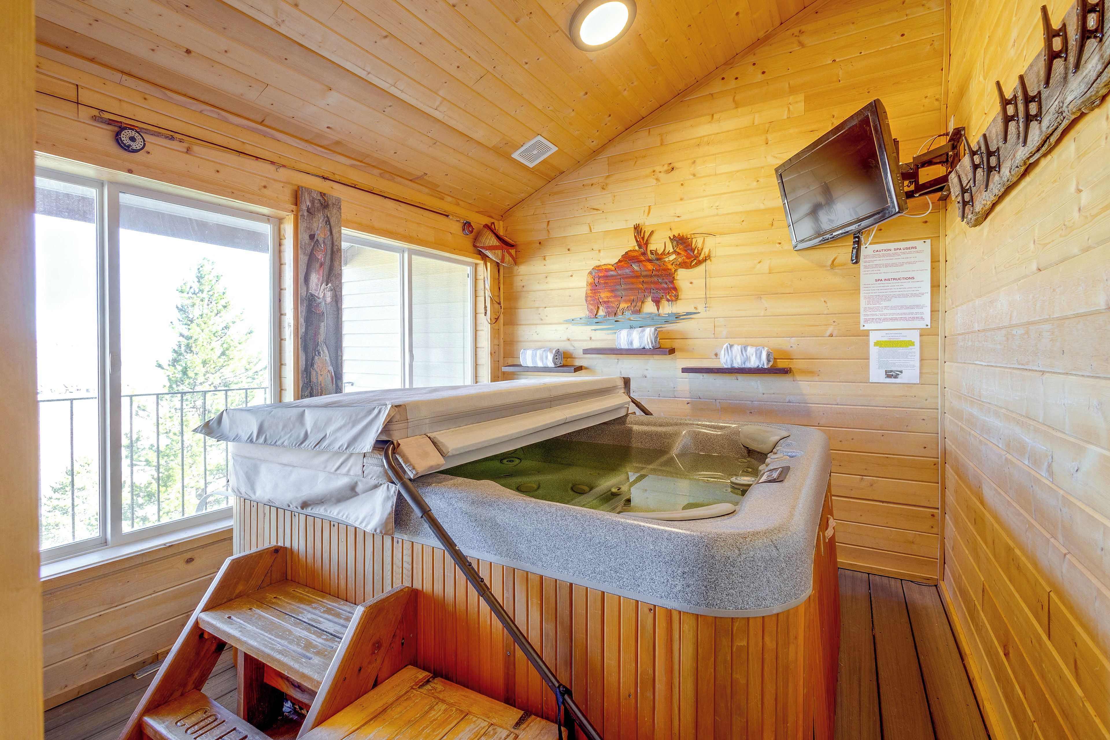 Ein Spa-Raum aus Holz mit Whirlpool, einer Holzbank und einem Wandfernseher.