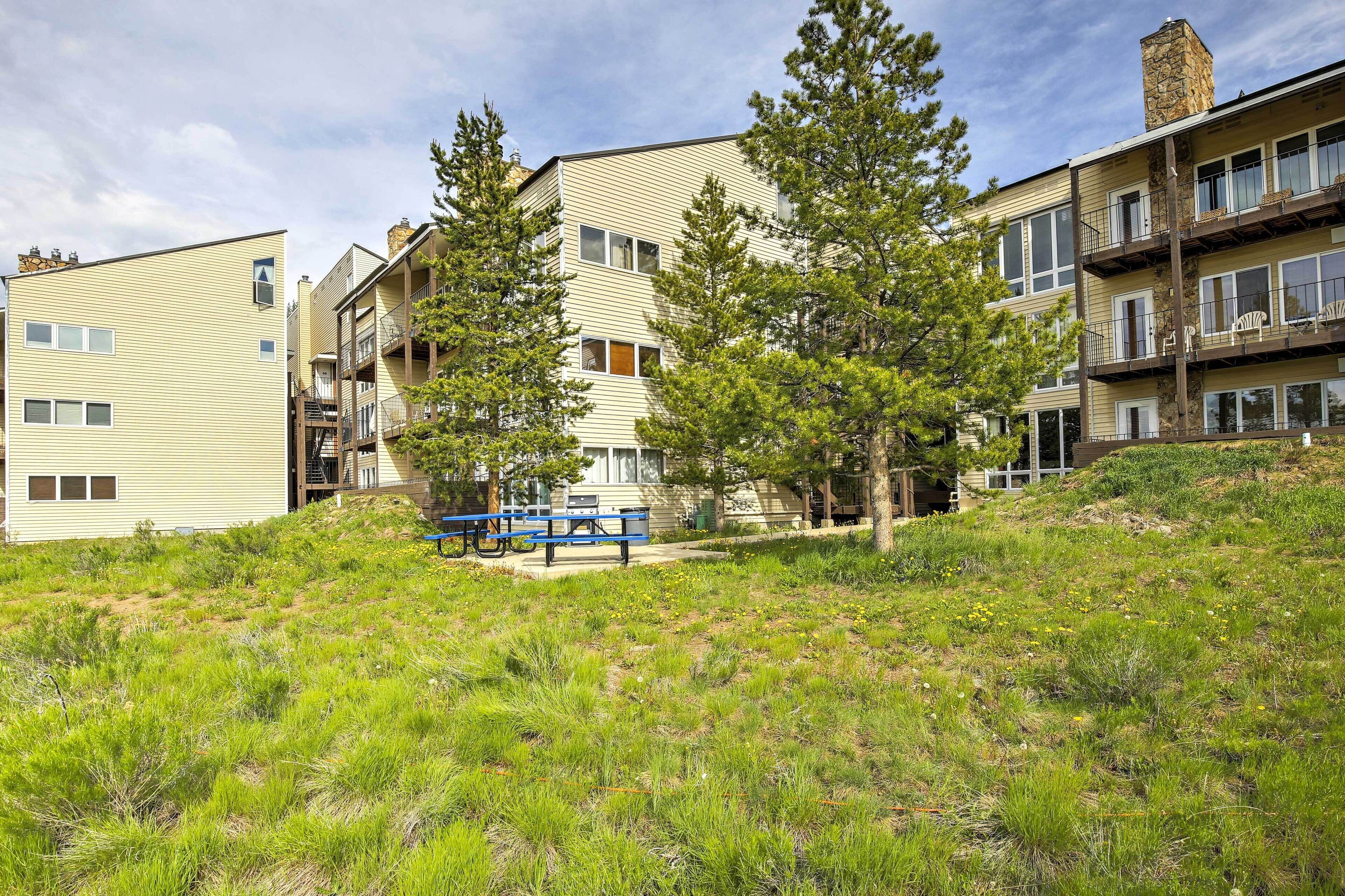 A multi-story residential building with a flat roof, a stone chimney, and a balcony with outdoor seating.