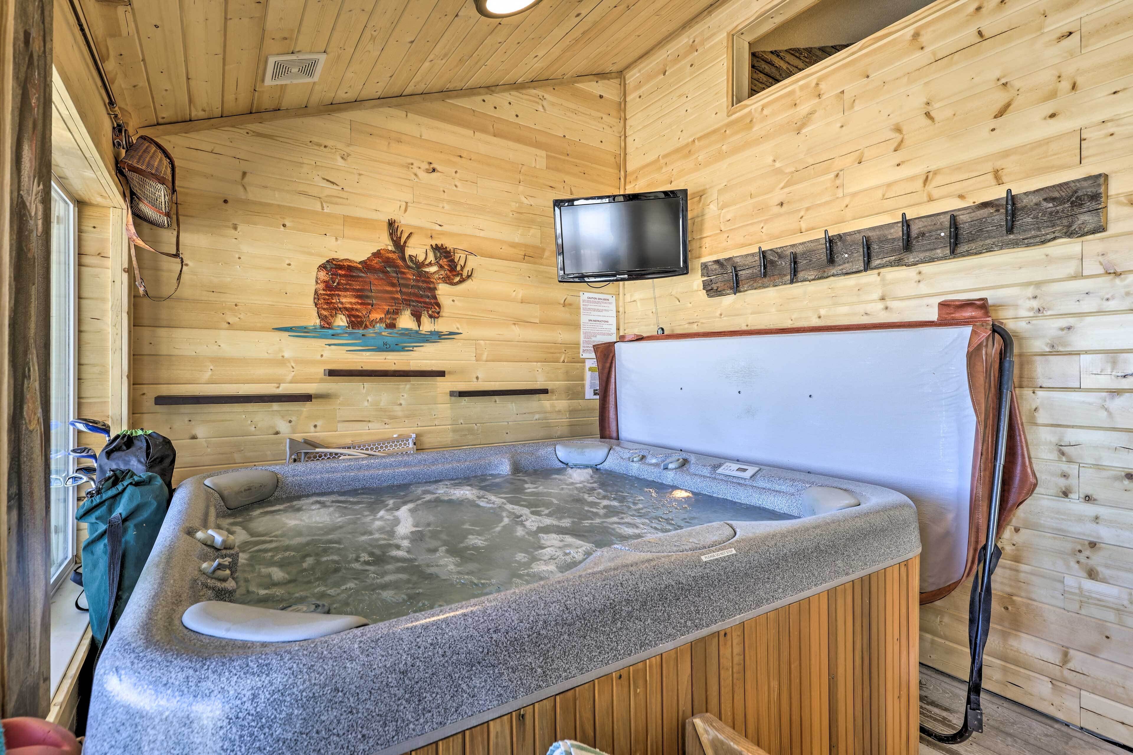 A wooden cabin interior with a hot tub, wooden walls, a mounted TV, and a mounted coat rack.