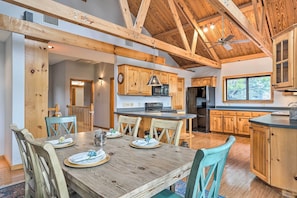 A spacious kitchen with wooden cabinets, a central island, and a dining area with a wooden table and chairs. - Lakehills Vacation Rental on Medina Lake (Pipe Creek)