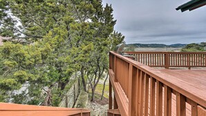 Una terraza de madera con vista a árboles y un paisaje lejano.
