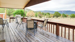 Eine Holzterrasse mit Sitzgelegenheiten und Blick auf eine gebirgige Landschaft.