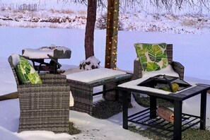 Outdoor wicker furniture with snow accumulation, a small table, and a tree with string lights. - John Day Lakehouse w/ a Great Outdoor Space! (John Day)