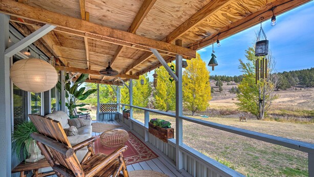 Eine überdachte Veranda mit Holzmöbeln, einem roten Teppich und hängenden Laternen.