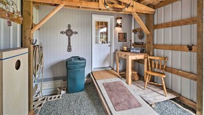 Ein rustikales Interieur mit Holzbalken, einer Tür, einem Tisch, einem Stuhl und einem Mülleimer.