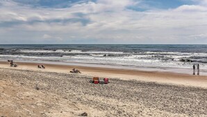 A beach with a sandy shore, a few people, and a few beach chairs. - Cozy Cottage < 2 Mi to Cape Hatteras Natl Shore! (Frisco)