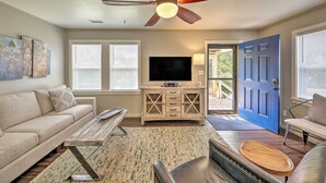 A living room with a sofa, coffee table, TV, and a ceiling fan. - Cozy Cottage < 2 Mi to Cape Hatteras Natl Shore! (Frisco)