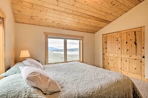 Ein Schlafzimmer mit einem großen Bett, einem Fenster mit Blick, einem hölzernen Kleiderschrank und einer Lampe auf einem Nachttisch.