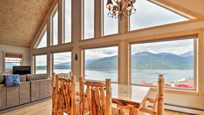 Une pièce spacieuse avec un plafond haut, de grandes fenêtres, une table à manger en bois et un coin salon confortable.