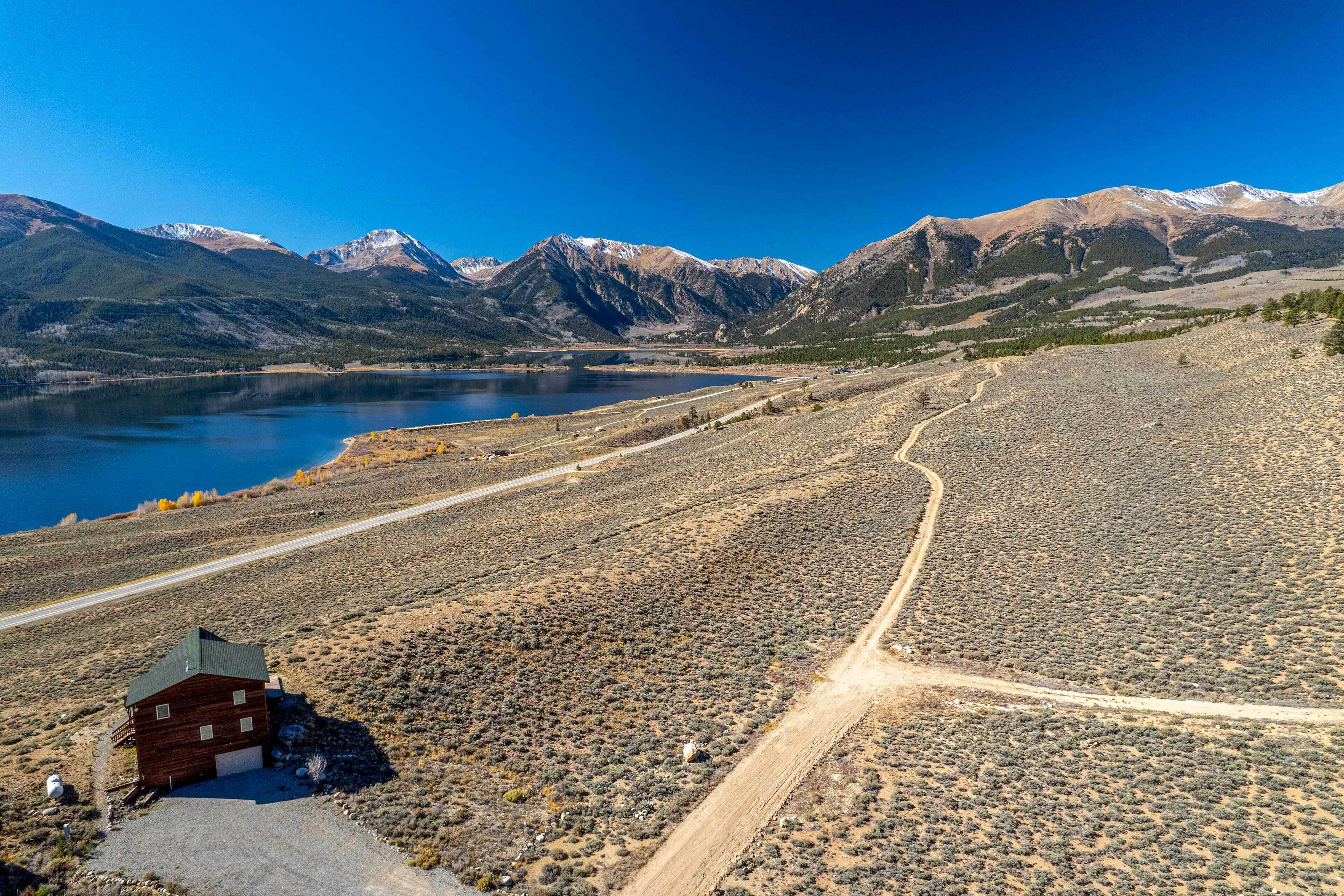 A remote cabin by a lake with mountains in the background.