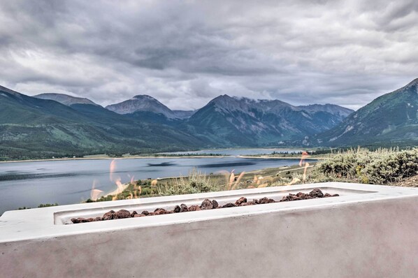 Une vue d’un lac entouré de montagnes, avec une corniche en béton au premier plan.