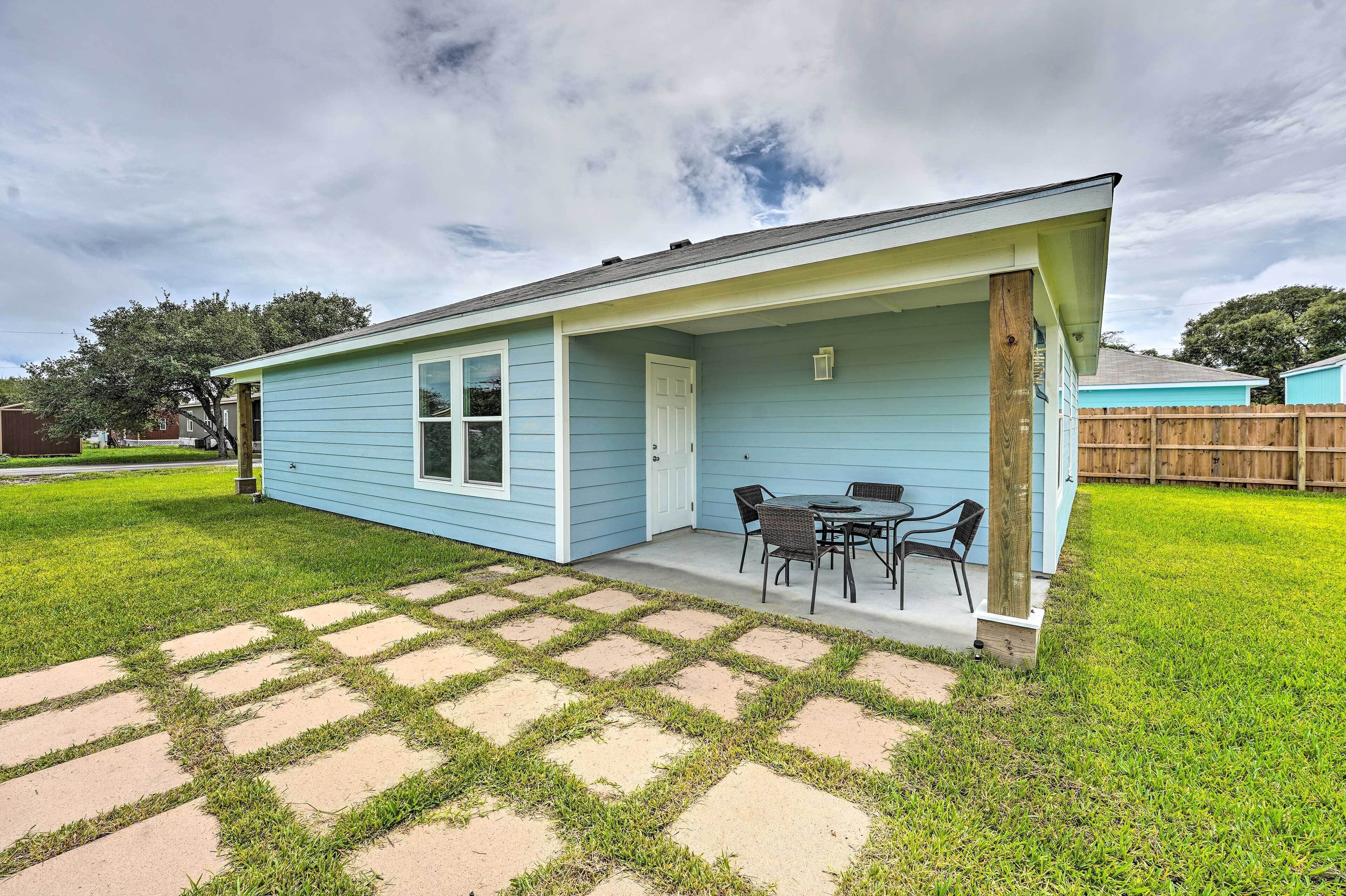 A light blue house with a covered patio, a small table, and chairs.