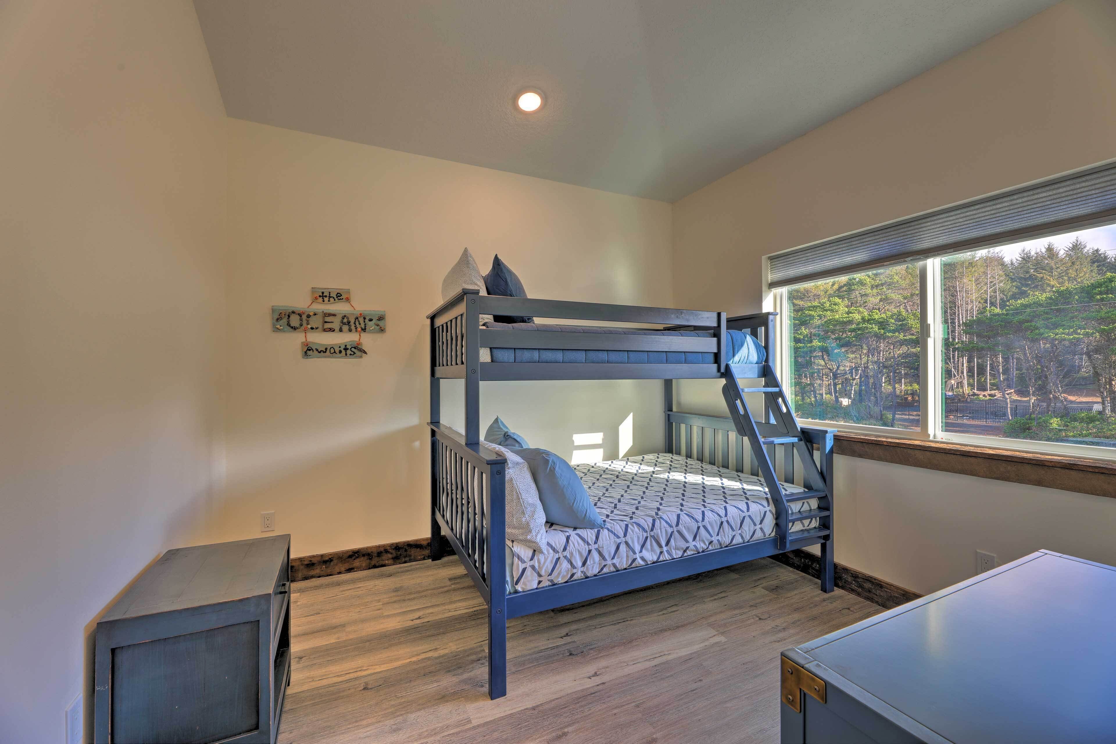 A bunk bed room with a window, a small desk, and a wall decoration.
