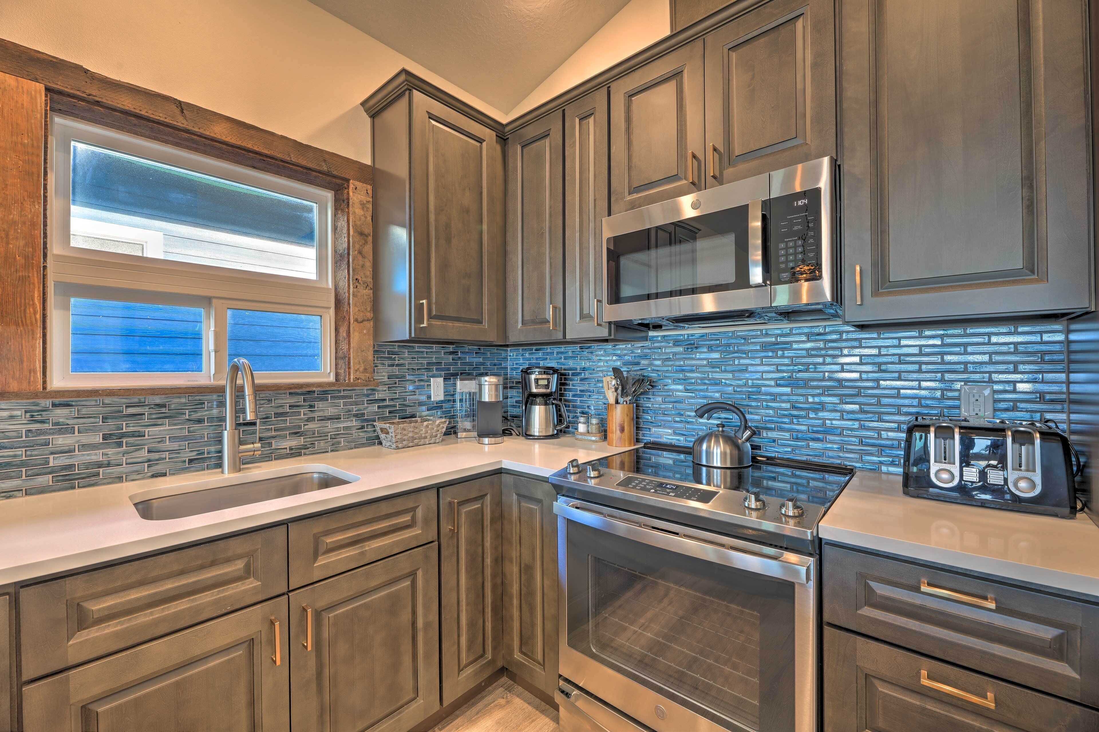 A modern kitchen with dark wood cabinets, a stainless steel microwave, a built-in oven, and a blue-tiled backsplash.