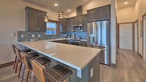 A modern kitchen with a large island, stainless steel appliances, and a stone backsplash. - Sanderling Sea Cottages, Unit 7 w/ Beach Access! (Waldport)