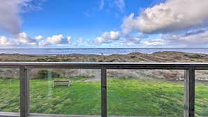 A coastal view from a wooden deck with a bench, grassy area, and rocky terrain. - Sanderling Sea Cottages, Unit 7 w/ Beach Access! (Waldport)