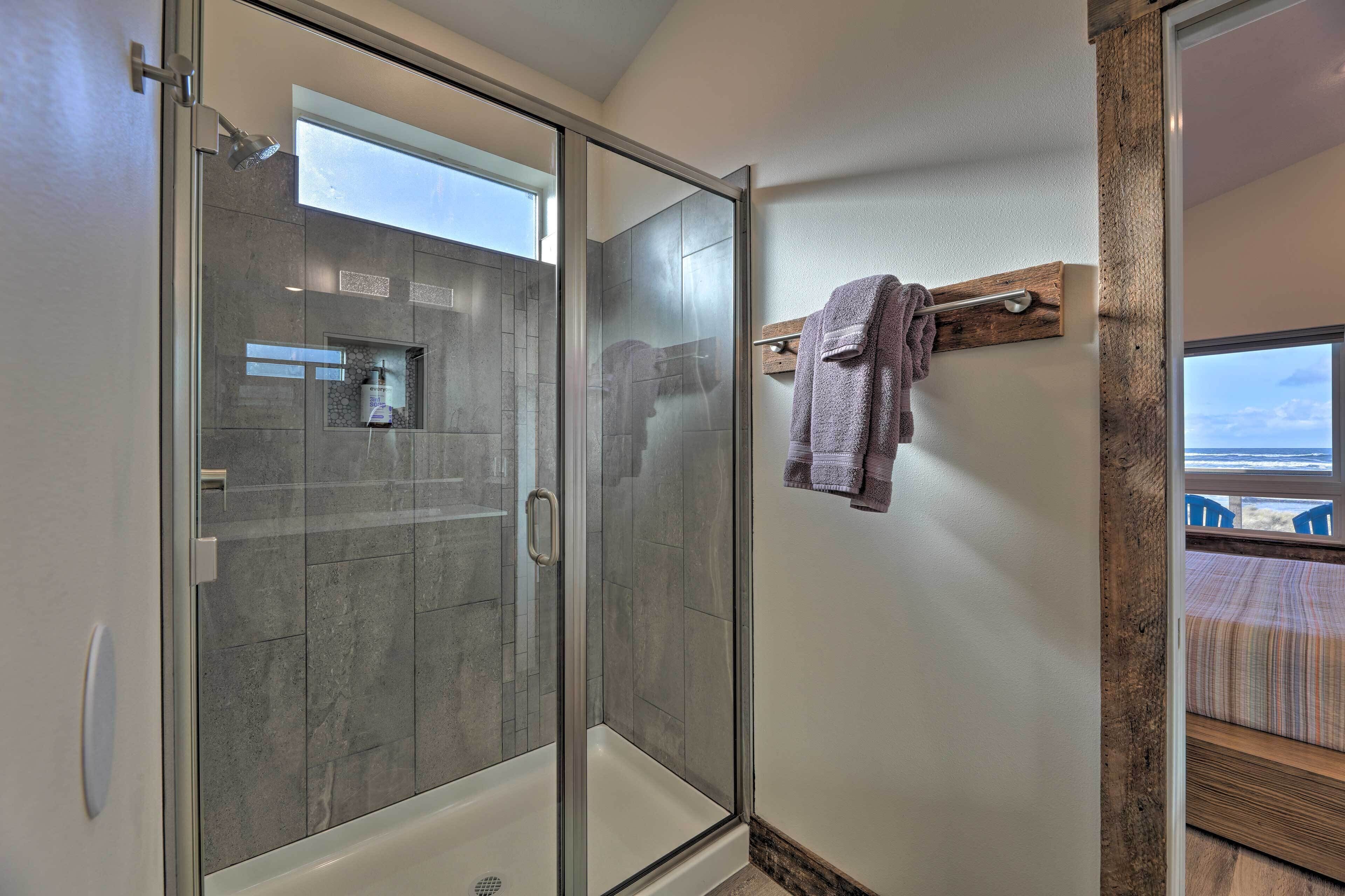 Une salle de bain moderne avec une douche à parois de verre, un porte-serviettes avec des serviettes et une vue sur l’extérieur.