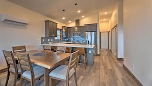 A modern kitchen with a central island, wooden dining table, and chairs. - Sanderling Sea Cottages, Unit 7 w/ Beach Access! (Waldport)