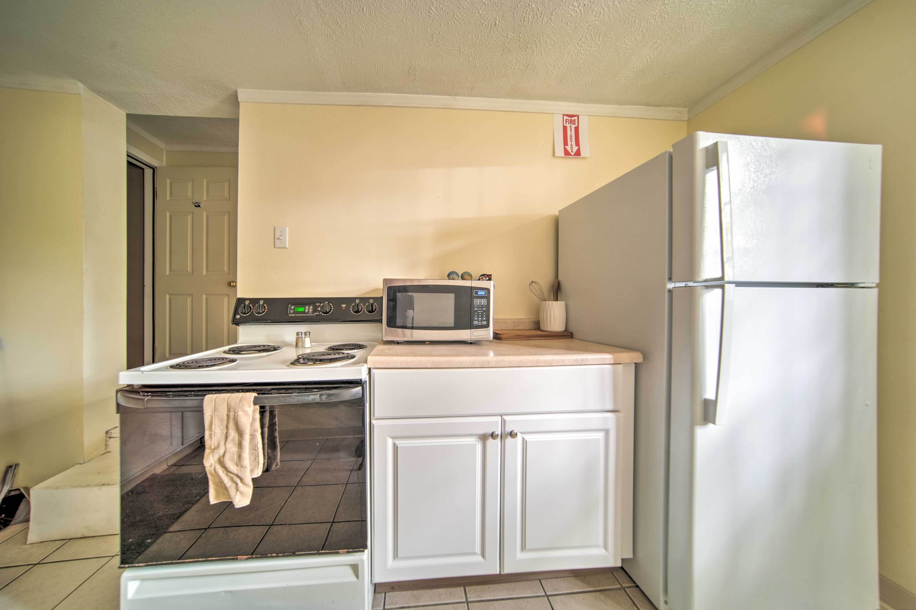 Una cocina compacta con estufa, microondas, horno y refrigerador.