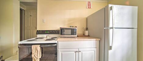 Una cocina compacta con estufa, microondas, horno y refrigerador.