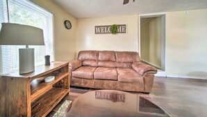 A living room with a leather couch, wooden coffee table, and a lamp. There is a 'WELCOME' sign on the wall and a clock. - Geneva-on-the-lake Cottage w/ Patio: Walk to Shore (Geneva)