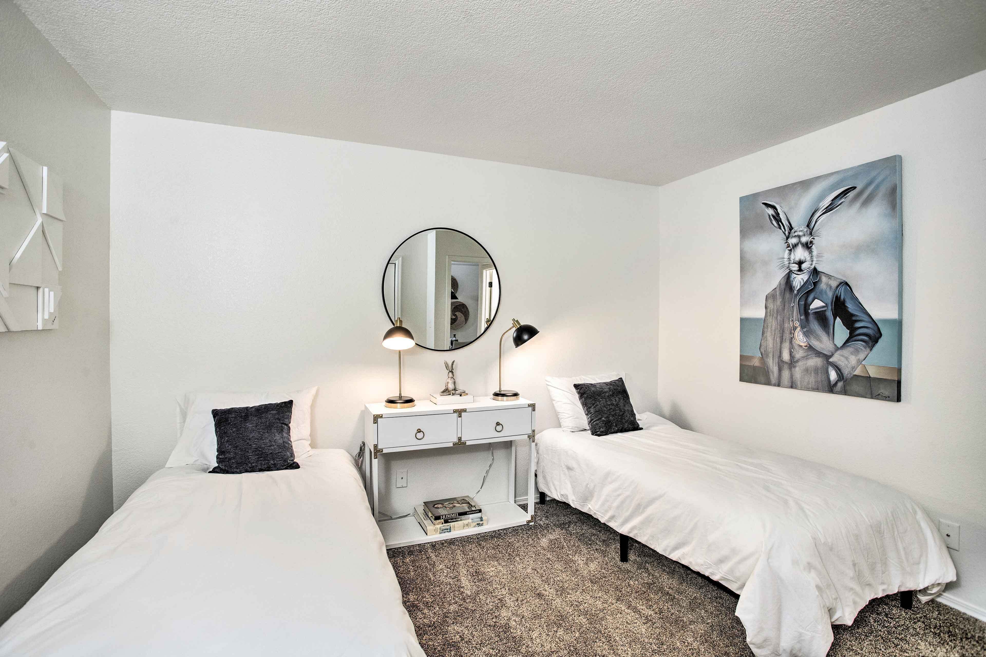 Une chambre avec deux lits simples, une commode avec un miroir et un tableau au mur.