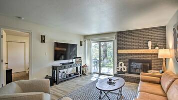 A modern living room with a fireplace, a flat-screen TV, and a comfortable seating area.