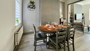 A dining area with a round wooden table, four chairs, and a modern wall decor. - Daubney House (Cleethorpes)