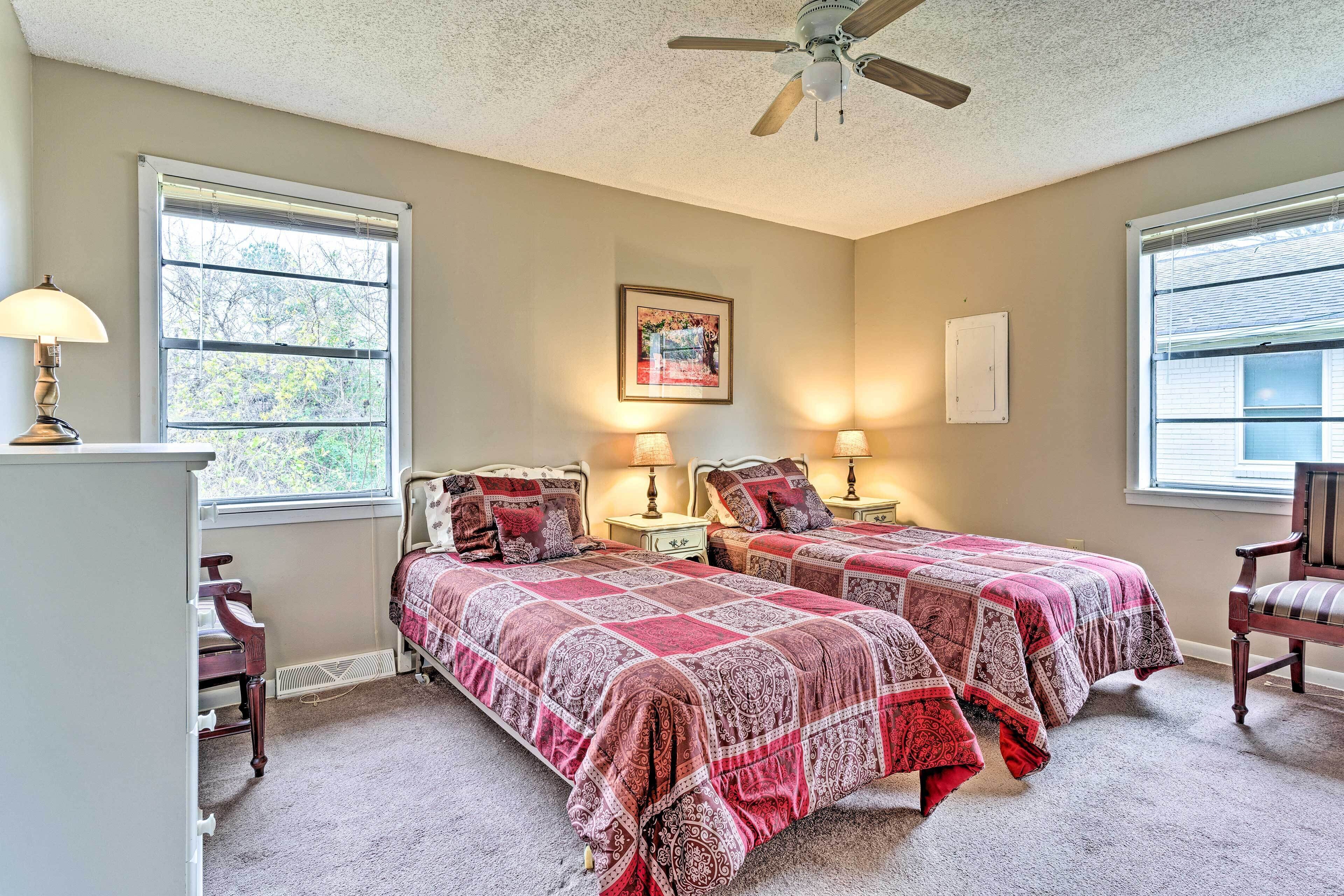 A bedroom with two beds, a ceiling fan, and a window with blinds.