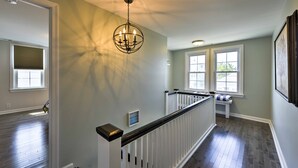 A hallway with a wooden floor, white railing, and a ceiling light fixture. - Charming Wildwood Hideaway w/ Private Pool & Deck! (Wildwood)