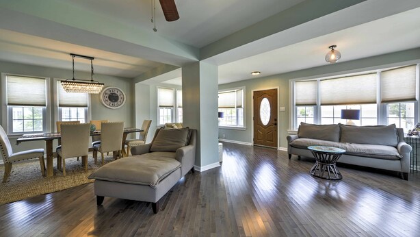 A spacious living room with hardwood flooring, a ceiling fan, a chandelier, and a dining area with a table and chairs. - Charming Wildwood Hideaway w/ Private Pool & Deck! (Wildwood)